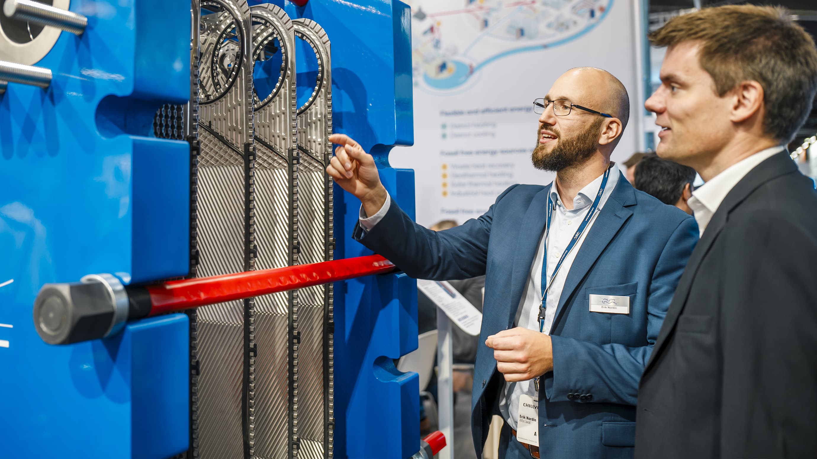 A male exhibitor is presenting his product to a trade fair participant